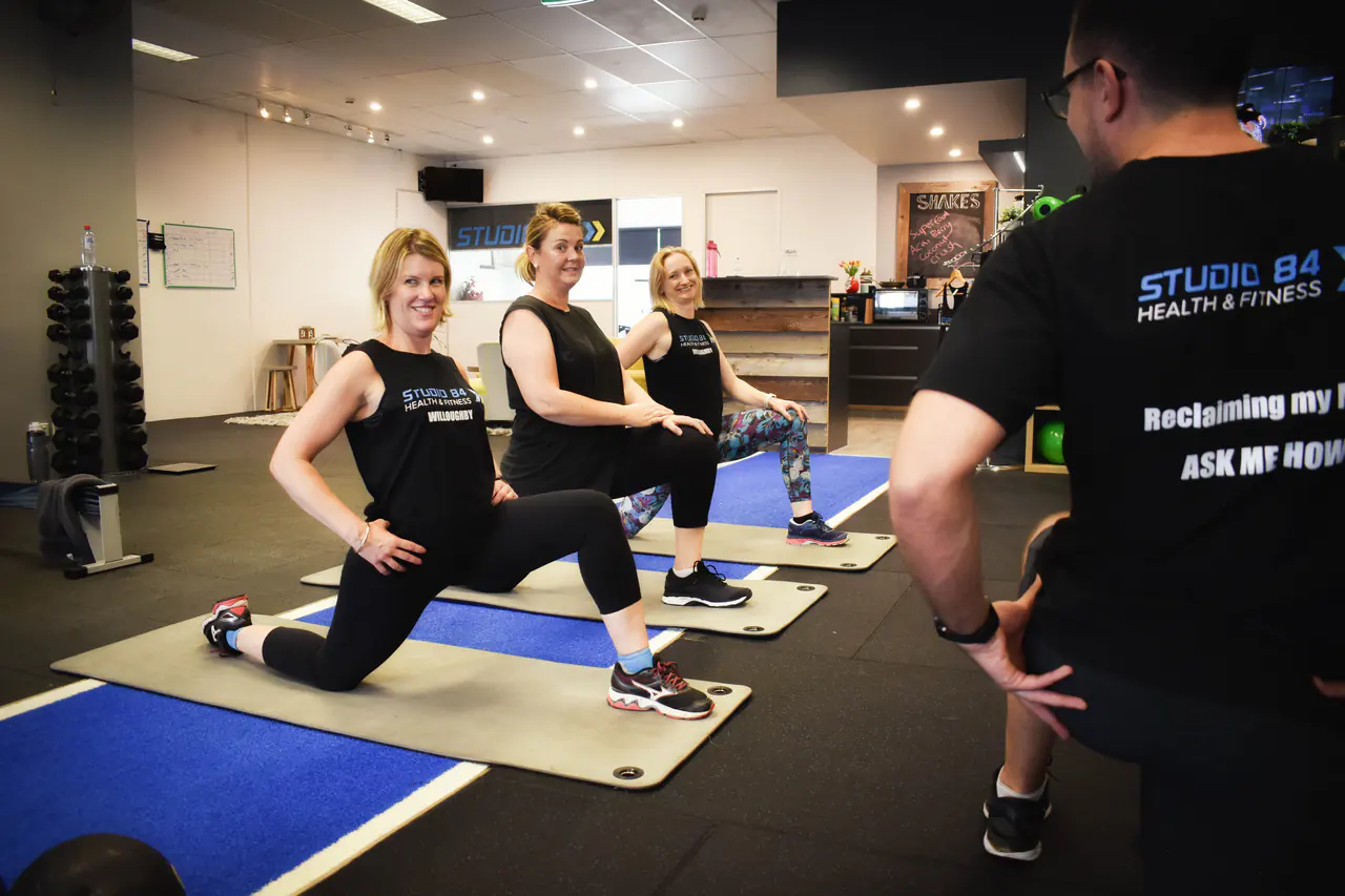 Members lunging on mats with a coach watching their form