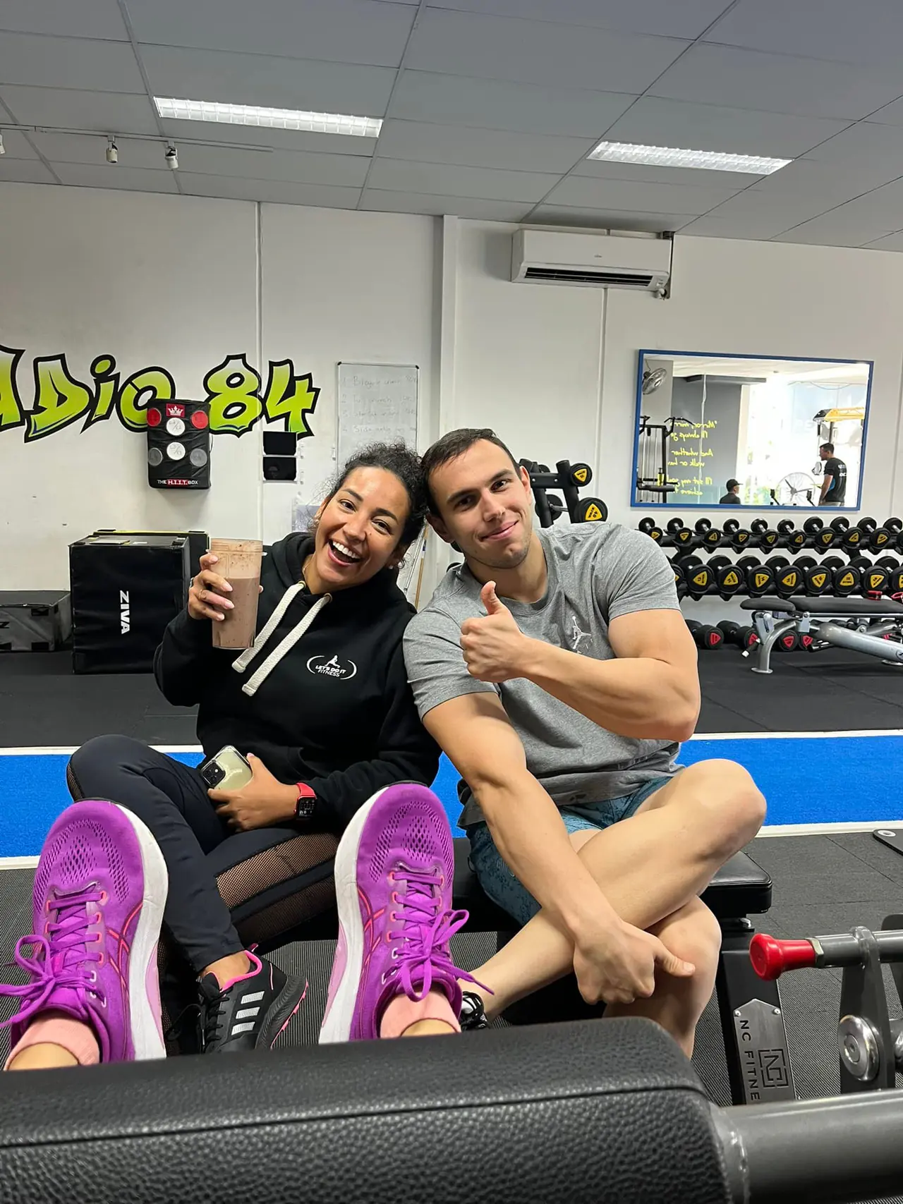 Coaches Mandy and Henrique laughing on the gym floor