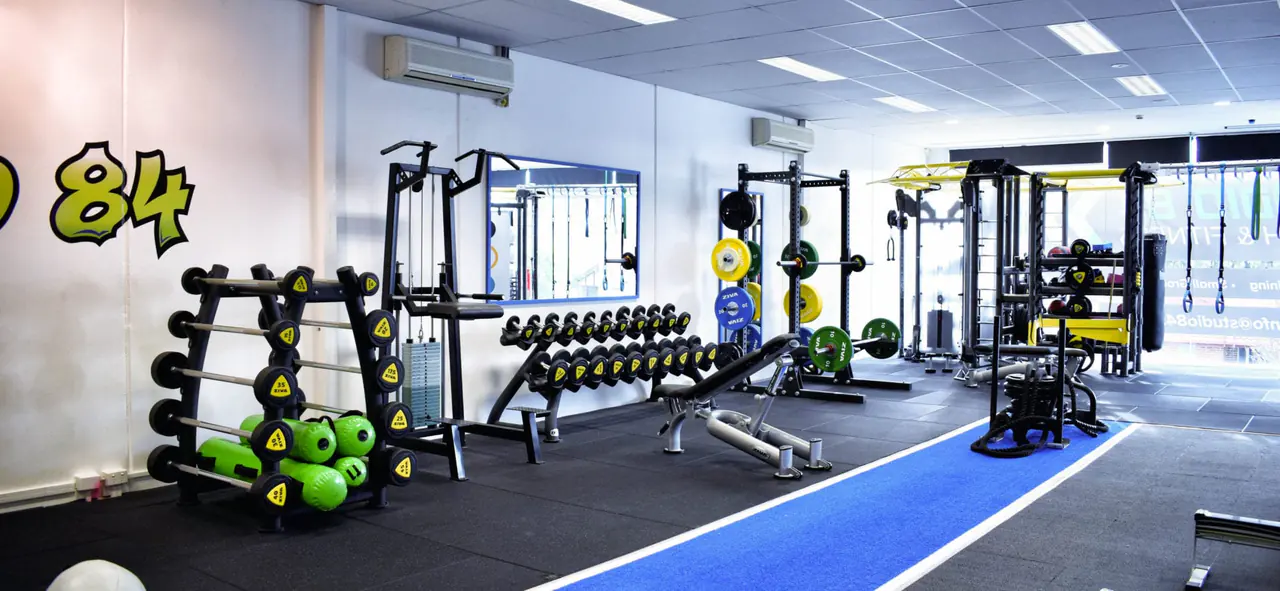 The gym floor with racks, dumbbells and the blue turf lane