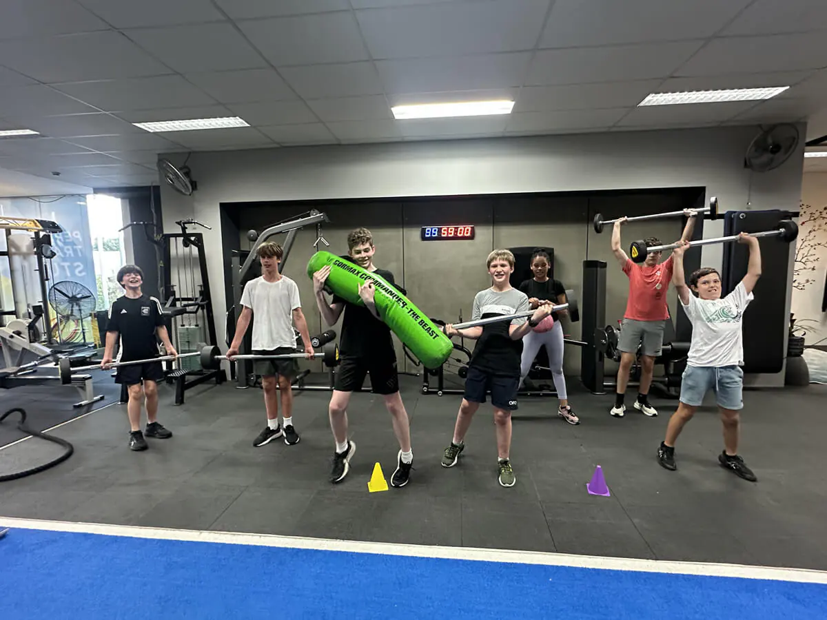 Kids lifting light bars with a coach
