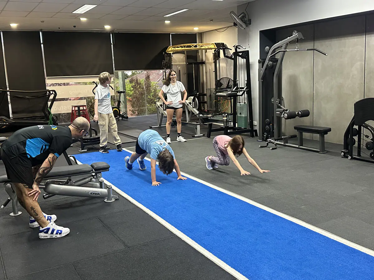 Kids doing bear crawls along the turf with their coach