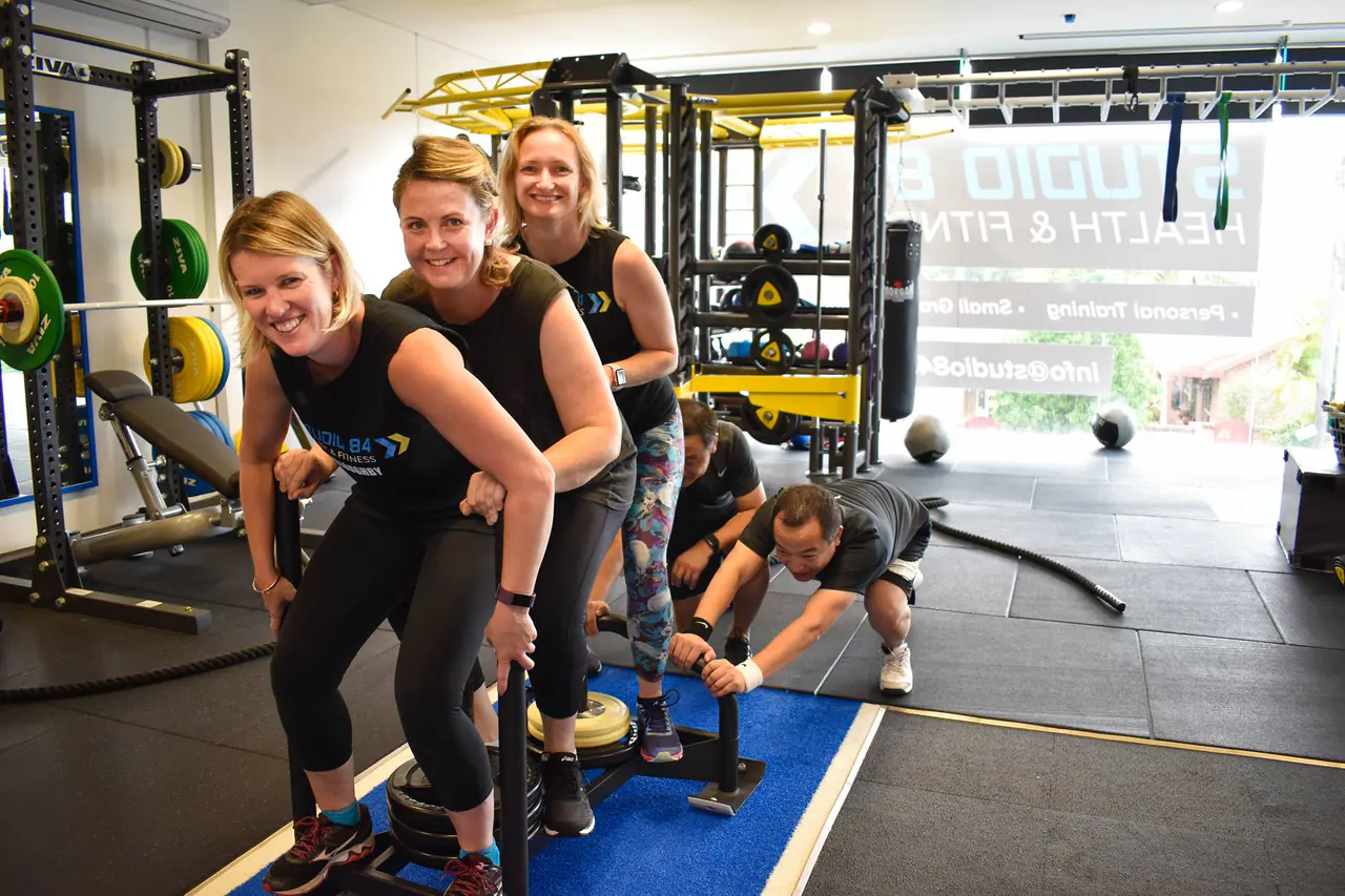Members laughing as they push sleds side by side