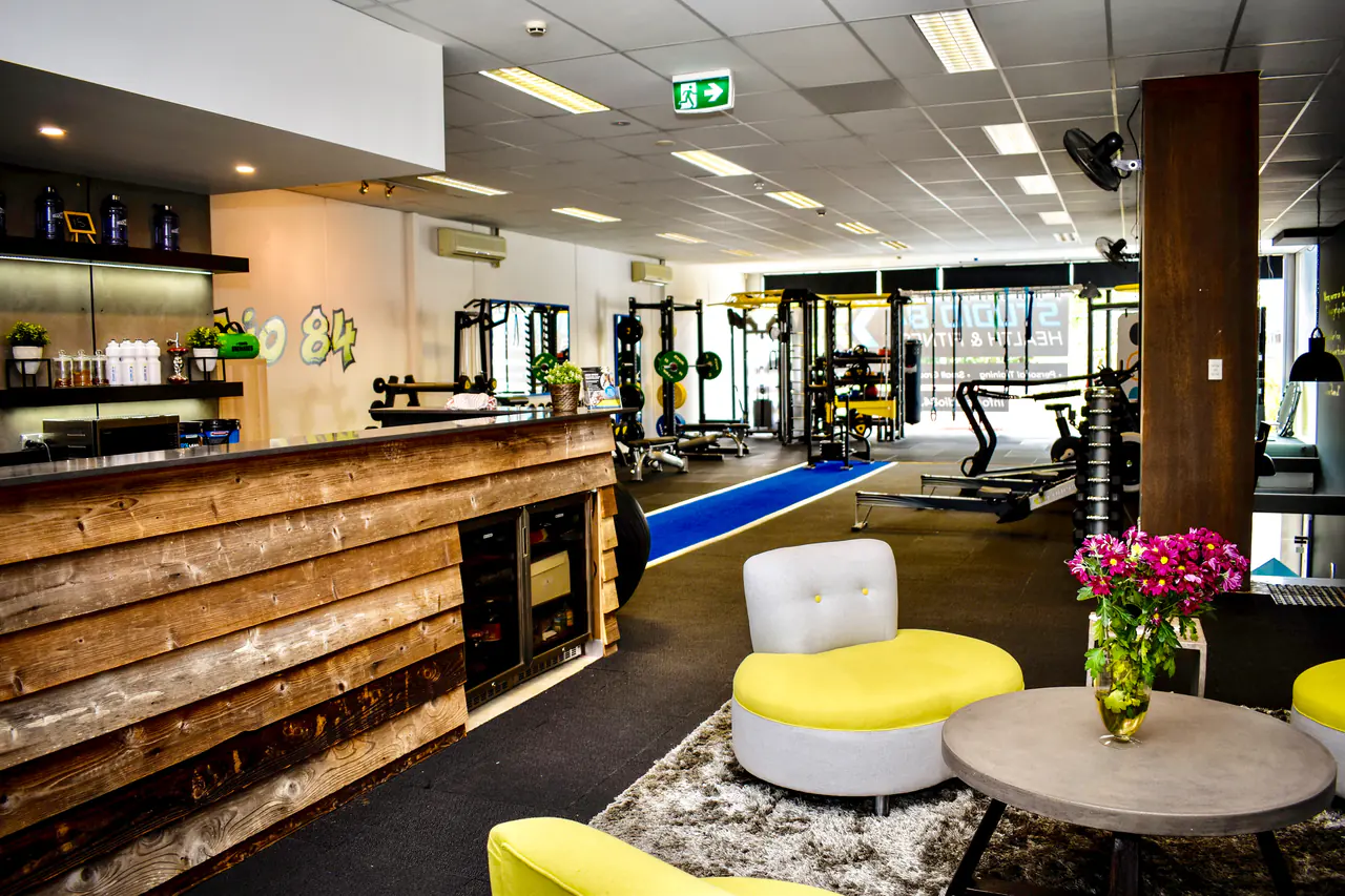 The reception bar and lounge with yellow chairs, looking through to the gym floor